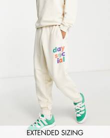 ASOS DESIGN ASOS Daysocial relaxed trackies with multi logo prints and seam detailing in ecru (part of a set)-White